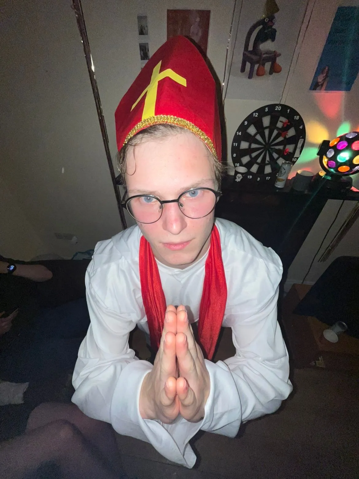 Wearing a playful red costume hat and posing seriously for the camera